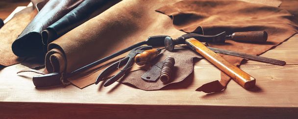 Shoemaker's work desk. Tools and leather at cobbler workplace. Set of leather craft tools on wooden background. Shoes maker tools on wooden table - Photo, Image