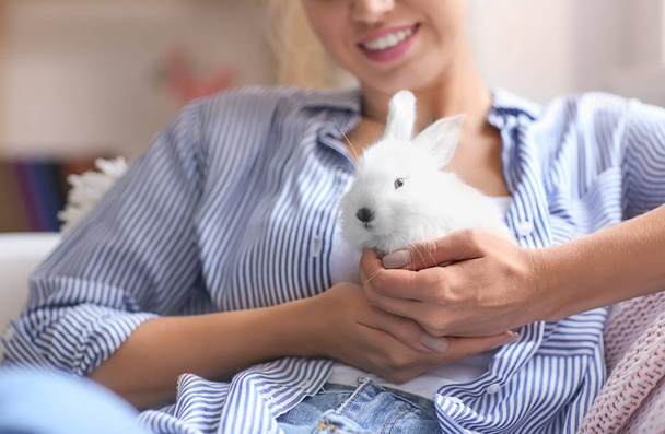 Beautiful young woman with cute rabbit at home, closeup - Foto, afbeelding