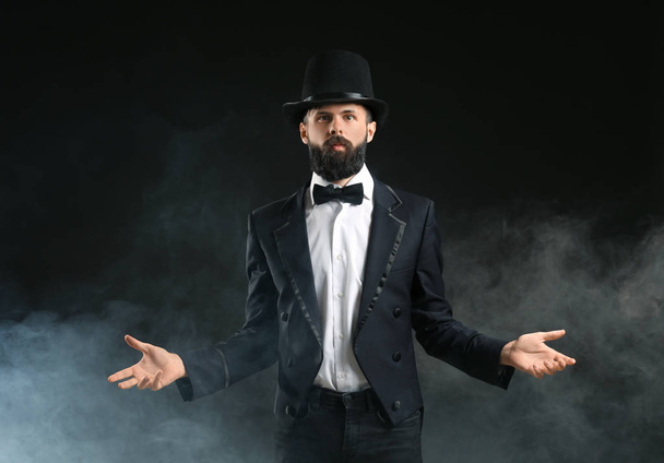 Magician showing tricks in smoke on dark background - Photo, Image