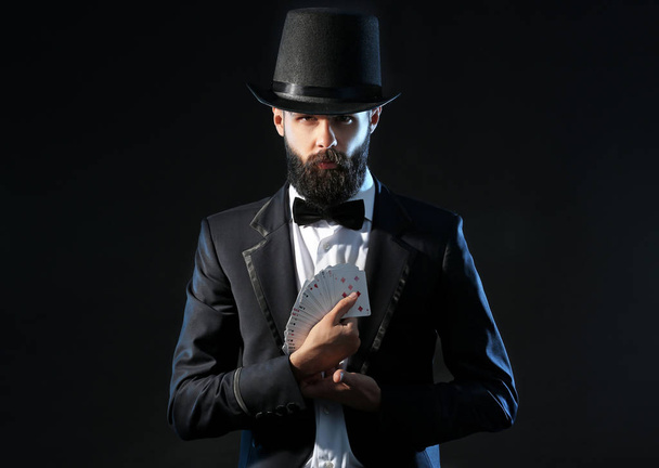 Magician with cards on dark background - Фото, зображення