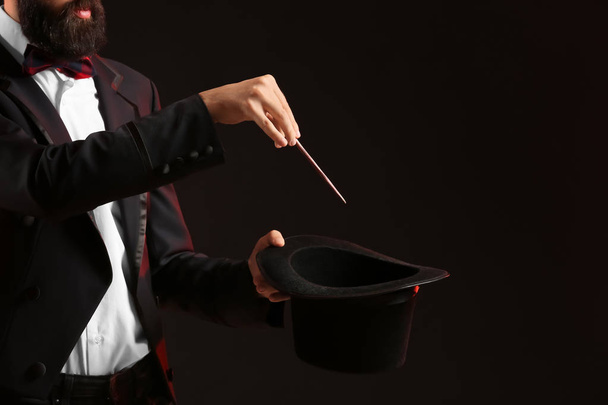 Magician showing tricks on dark background - Photo, Image