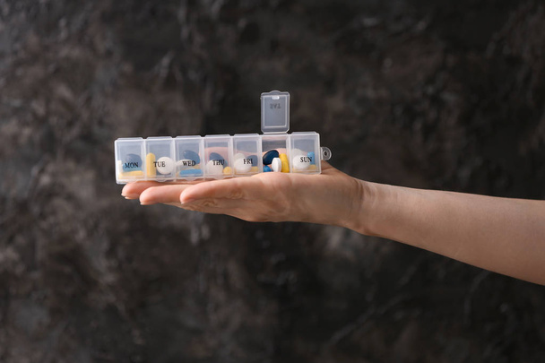 Mulher segurando recipiente de plástico com diferentes pílulas em fundo cinza
 - Foto, Imagem