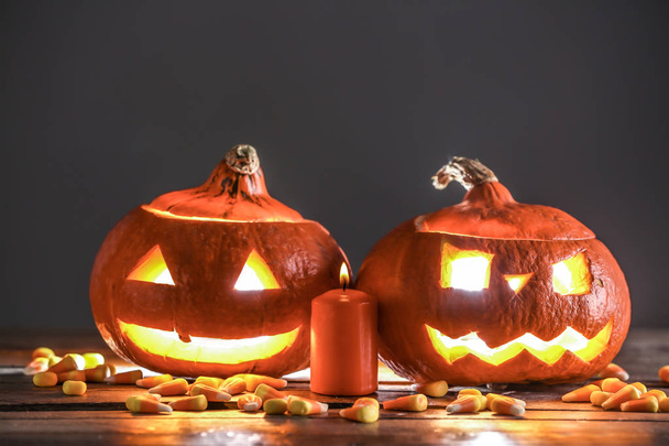 Calabazas de Halloween con caramelos y vela encendida en la mesa de madera
 - Foto, imagen