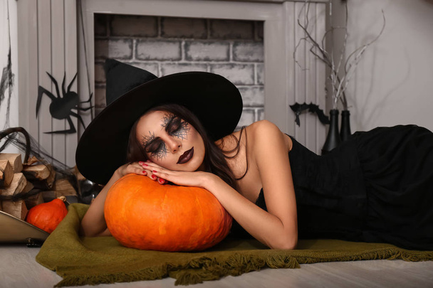 Hermosa mujer vestida de bruja en la habitación decorada para Halloween
 - Foto, imagen