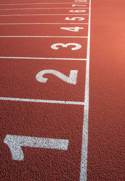 Carriles blancos en la alfombra roja del anillo de atletismo
 - Foto, Imagen