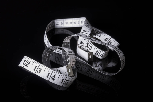 A white measuring tape on black background with reflection - Photo, Image