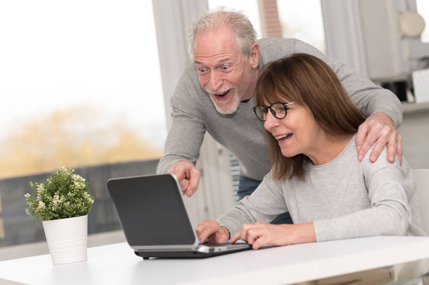 Ευτυχισμένο ζευγάρι που έχοντας μια υπέροχη έκπληξη σε φορητό υπολογιστή - Φωτογραφία, εικόνα
