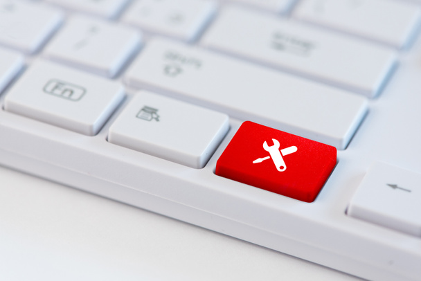 Rode toets met pictogram van de hulpprogramma's van de werkzaamheden op witte laptop toetsenbord. - Foto, afbeelding