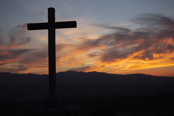 Tema religioso, vista de la cruz católica en sombra negra, con fantástica puesta de sol con colores cálidos y montañas como fondo, en Viseu, Portugal
 - Foto, Imagen
