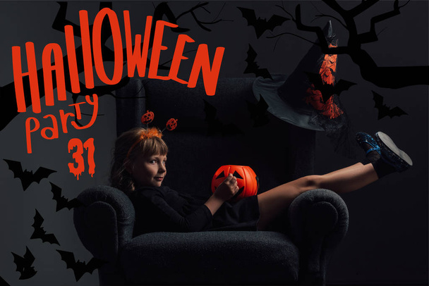 entzückendes Kind im Halloween-Kostüm im Sessel im dunklen Raum mit dem Schriftzug "halloween party 31" - Foto, Bild