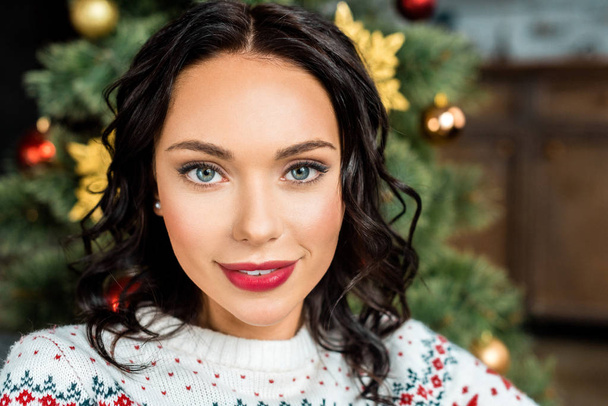 カメラ近くの自宅のクリスマス ツリーを見て魅力的な若い女性の肖像画  - 写真・画像