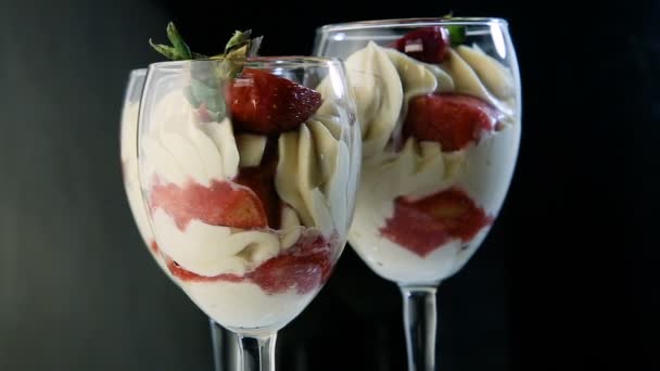 three hight glasses with tasty white mousse creamy dessert with sliced strawberry spin around on black mirror background - Footage, Video