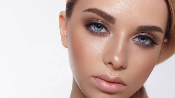 Glamour portrait of beautiful woman model with fresh daily makeup and romantic wavy hairstyle. Fashion shiny highlighter on skin, sexy gloss lips make-up and dark eyebrows - 写真・画像