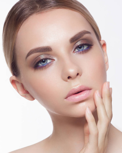 The young woman touches a face, showing gentle care behind skin. Bright blue eyes with a bright gentle make-up, chubby lips. Spa, cosmetology, ijektion - Foto, imagen