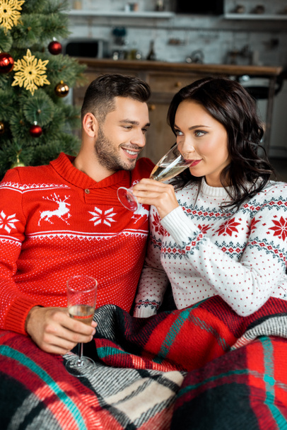 επιλεκτική εστίαση του ζευγάρι ceebrating με ποτήρια σαμπάνια στον καναπέ κοντά στο χριστουγεννιάτικο δέντρο στο σπίτι - Φωτογραφία, εικόνα