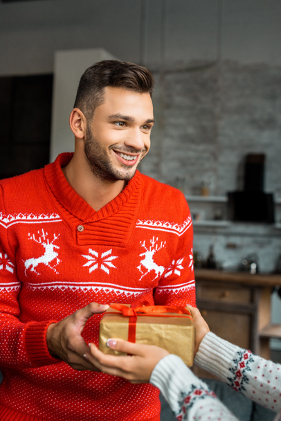 smiling young man gifting christmas present box to girlfriend at home - Foto, Imagen