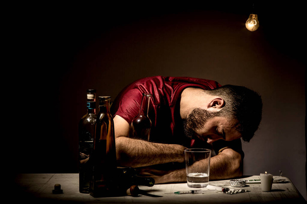 Young man with beard, lost in the vices of alcoholism, smoking and drug addiction - Foto, Imagen