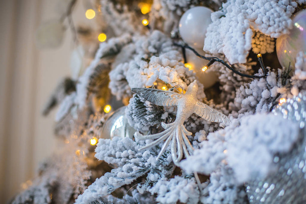 A toy in the form of a bird on a decorated Christmas tree. Christmas tree lights on the Christmas tree - Foto, imagen