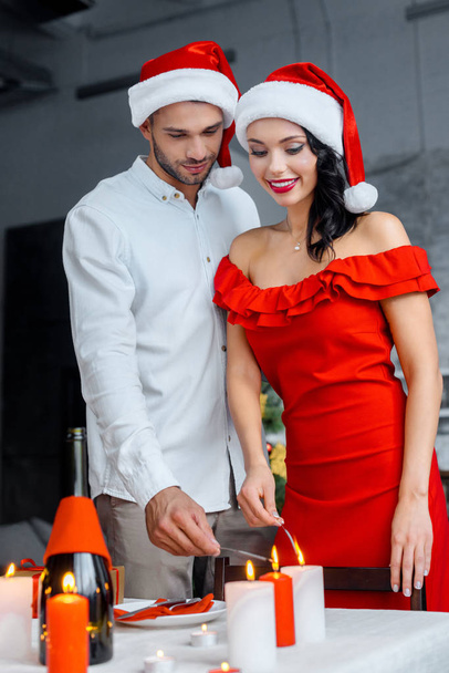 giovane coppia in cappelli di Natale brucia bastoncini scintillanti da candele a casa
 - Foto, immagini