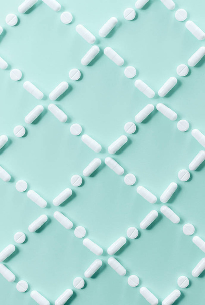 Pattern of white pills and tablets on a green background. Medical concept - Photo, Image