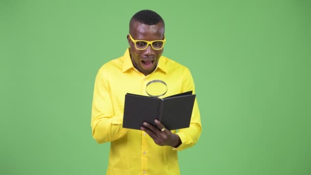 Young happy African nerd businessman reading book - Séquence, vidéo