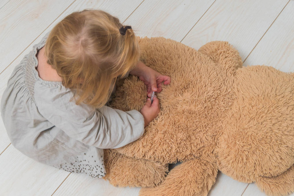 girl, a child plays doctor, makes a shot of insulin toy bear - Zdjęcie, obraz