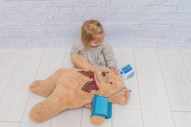 the girl, child measures the pressure of the toy bear, plays doctor - Photo, Image