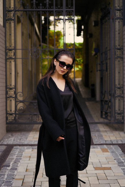 Gorgeous young brunette woman in black clothes posing on the street  - Foto, afbeelding
