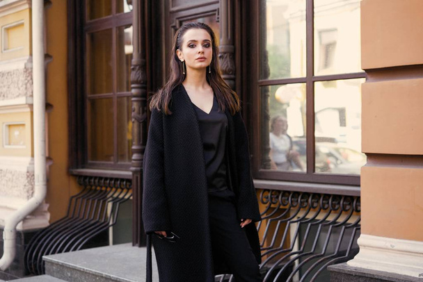 Gorgeous young brunette woman in black clothes posing on the street  - Fotografie, Obrázek