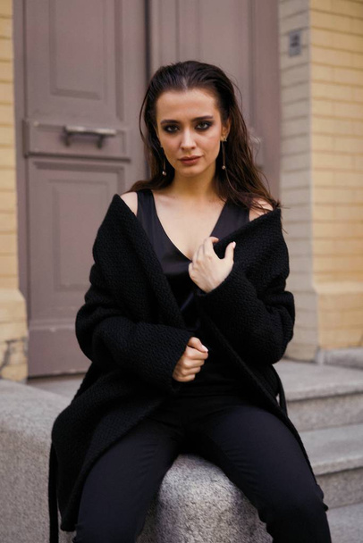 Gorgeous young brunette woman in black clothes posing on the street  - Photo, image
