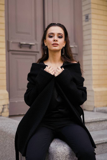 Gorgeous young brunette woman in black clothes posing on the street  - Fotoğraf, Görsel