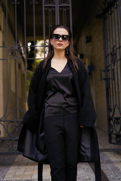 Gorgeous young brunette woman in black clothes posing on the street  - Foto, Imagen