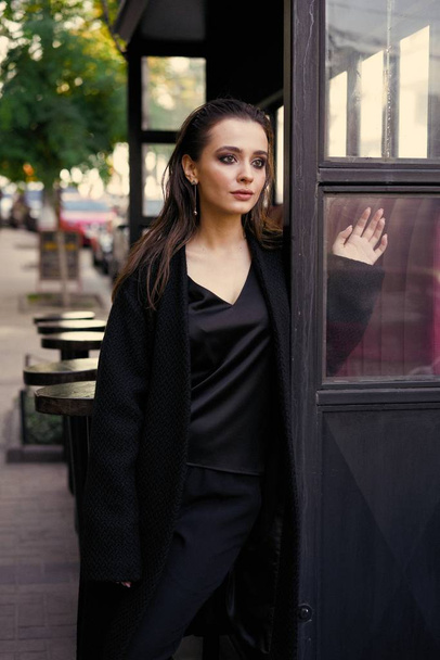 黒い服を着てポーズ豪華な若いブルネットの女性 - 写真・画像