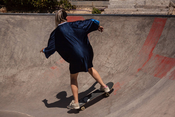 Młoda kobieta z miejskim stylu robi skateboarding w skatepark.  - Zdjęcie, obraz