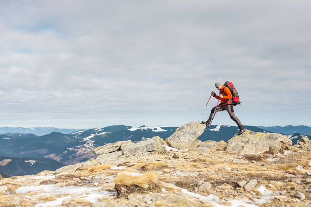 Klimmer met een rugzak op de top. Een man ging op de berg, mensen reizen door de prachtige wildernis, man klom naar de top van een berg en genieten van zijn succes. Winter wandeling. - Foto, afbeelding