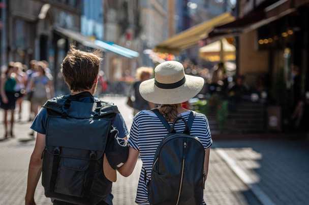 A couple of people with backpacks walking along the street. View from the back. - Photo, Image