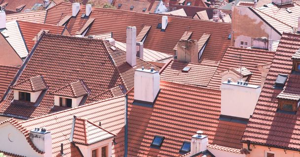 Texture is the roofs of tiled old buildings. Background of the orange roof tiles on historic buildings in the old city. Roofs of Prague, Czech Republic close-up. - Foto, afbeelding