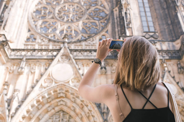 Toeristische meisje pikt de oude gotische kerkgebouw op een smartphone. Toeristische gefotografeerde St. Vituskathedraal - Foto, afbeelding