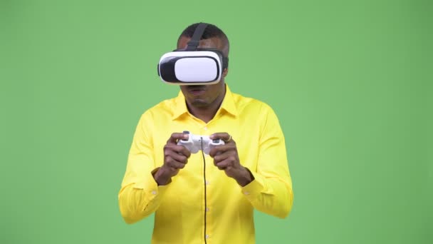 Young African businessman playing games while using virtual reality headset - Video, Çekim