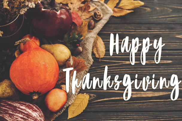 Happy Thanksgiving tekst op pompoen, herfst groenten met kleurrijke bladeren, eikels, noten, bessen op houten rustieke tafel, plat leggen. De kaart van de groet van de seizoenen. Sfeervolle afbeelding - Foto, afbeelding