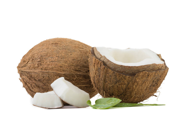Een close-up beeld van gesneden in de helft en hele kokosnoten geïsoleerd op een witte achtergrond. Het concept van exotische vruchten met bladeren vol vitaminen. - Foto, afbeelding