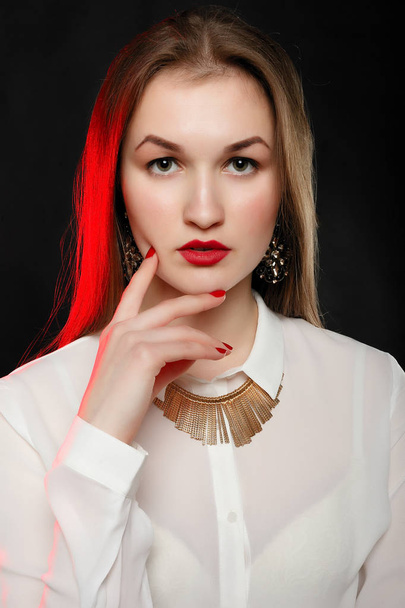 Fashionable woman in bright red coat and white shirt, with a gold necklace posing in studio, looking at camera. cold season. Autumn or winter look. - Fotó, kép