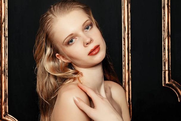 Beauty fashion model girl natural makeup wet hair on black gold background in warm tones. Portrait of young woman with fashion makeup - Φωτογραφία, εικόνα