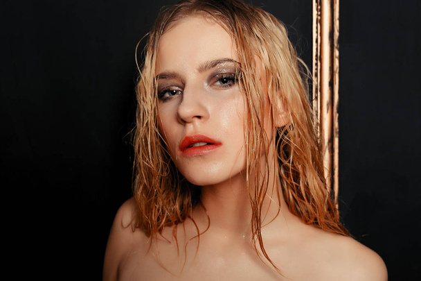 Beauty fashion model girl natural makeup wet hair on black gold background in warm tones. Portrait of young woman with fashion makeup - Photo, Image