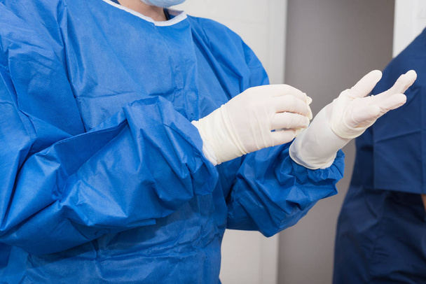 Медсестра надягає хірургічні рукавички
 - Фото, зображення
