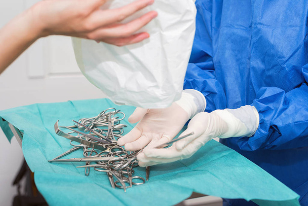 scrub verpleegkundige bereidt medische instrumenten voor de operatie - Foto, afbeelding