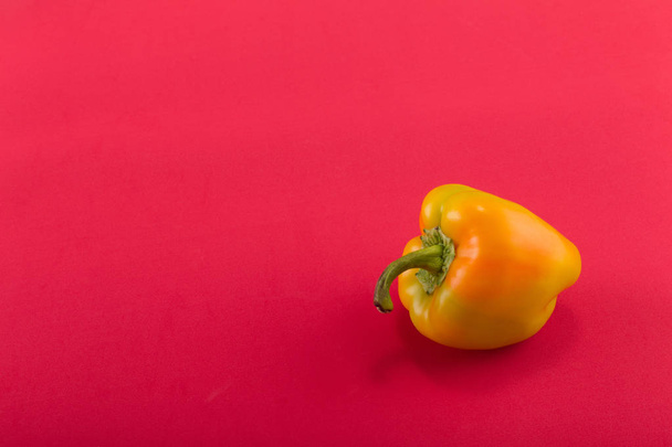 Sweet bellpepper. Orange-yellow sweet bellpepper on a red background. One. Studio light. Top view - Foto, immagini