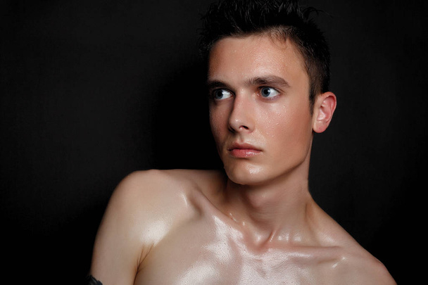 Handsome young man isolated. Beauty portrait of shirtless muscular man is standing on black background and looking at camera. Men's health. - Фото, зображення