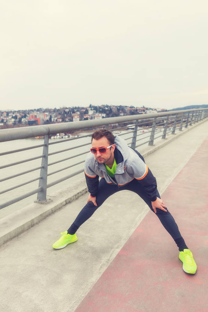 Kentsel jogger bir köprüde germe. - Fotoğraf, Görsel