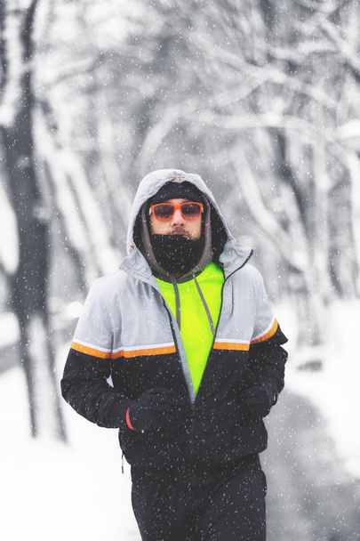 Ο άνθρωπος άσκηση και τρέξιμο σε εξωτερικούς χώρους σε χιονισμένο πάρκο - Φωτογραφία, εικόνα